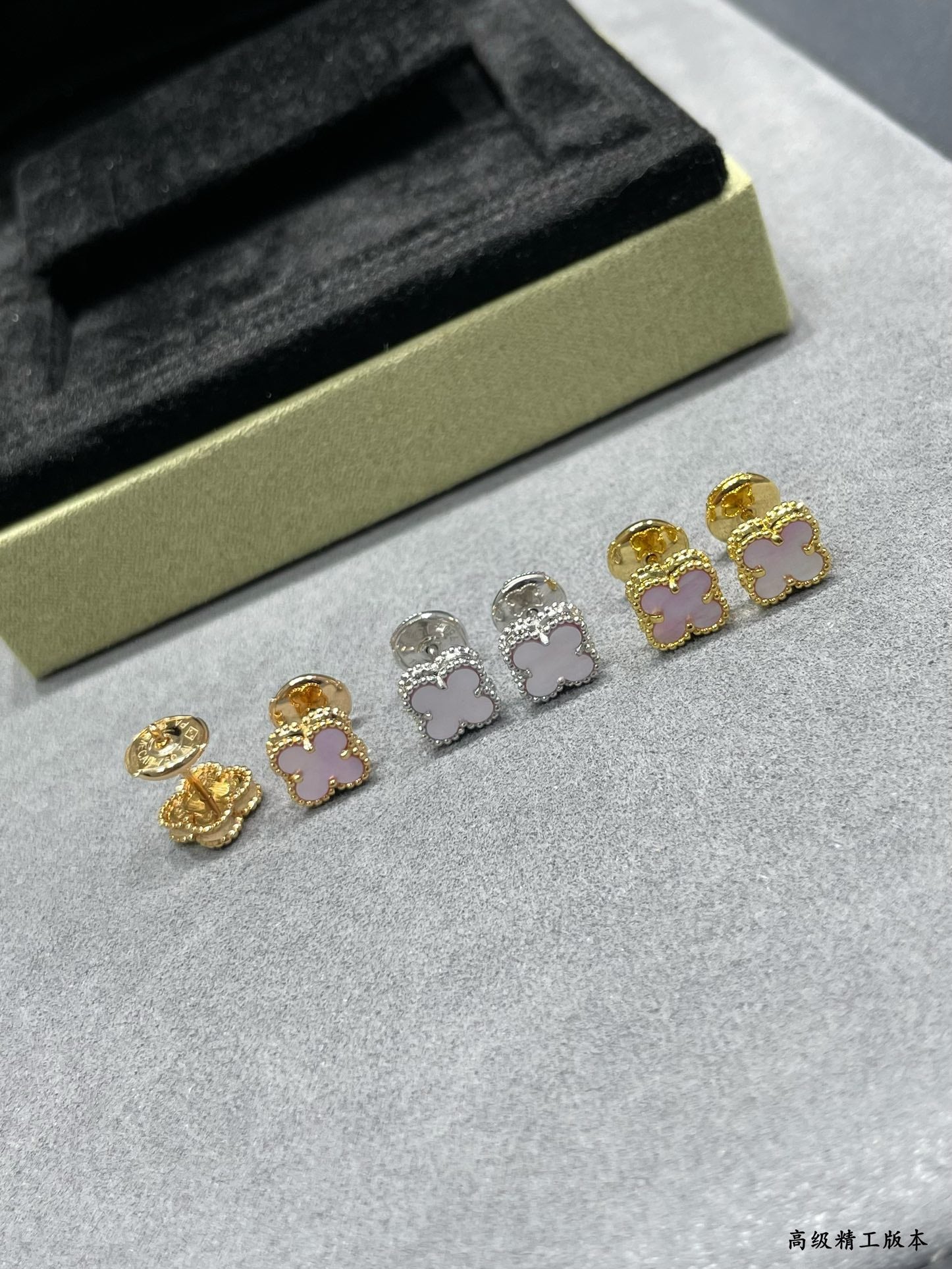 Four-leaf clover stud earrings set on a light surface, mixed gold and silver with pink