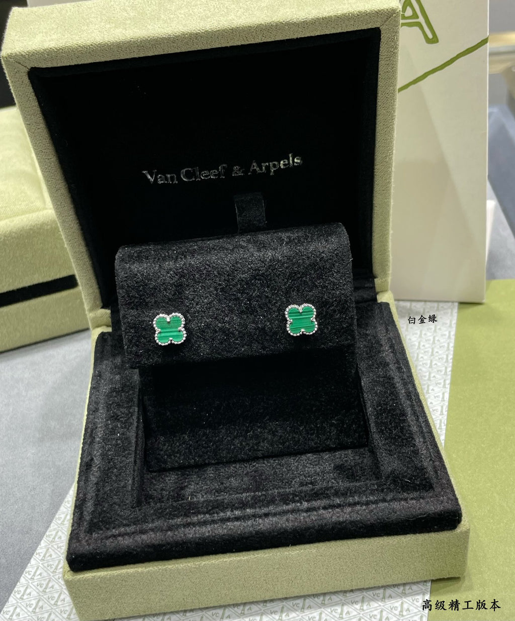 Van Cleef & Arpels clover stud earrings on black velvet inside gift box, green enamel