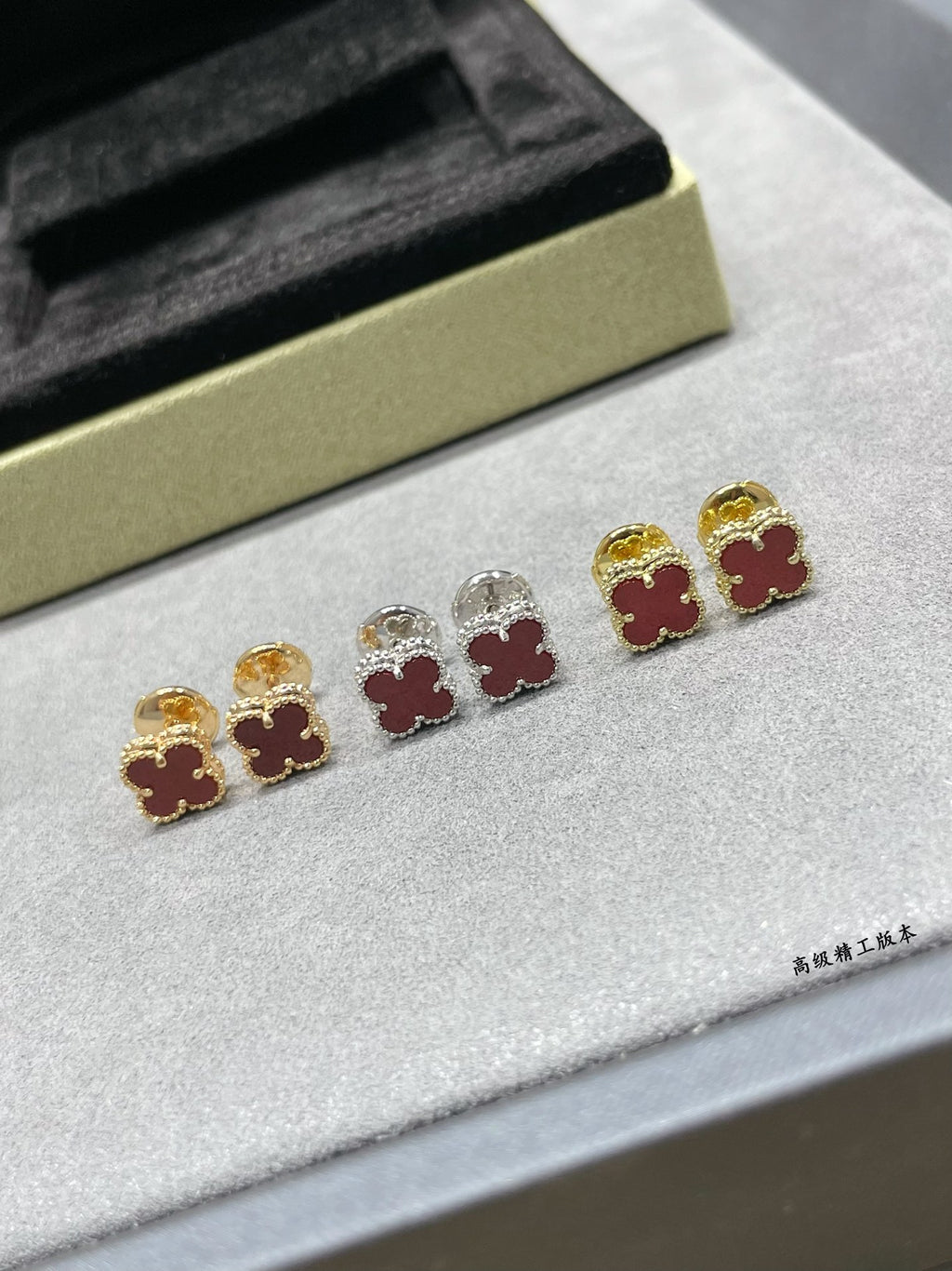 Clover motif stud earrings with mixed gold, silver, and red enamel pairings