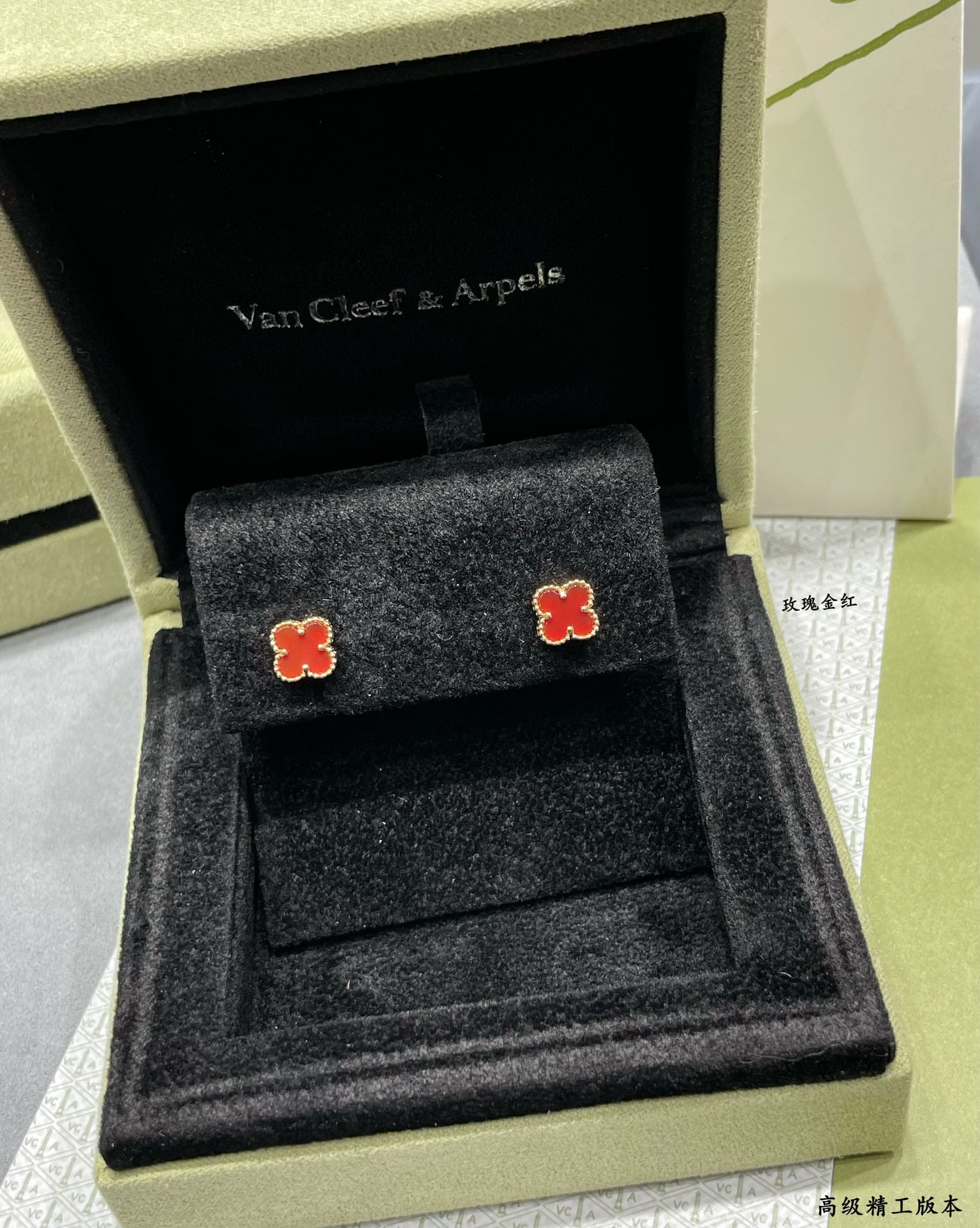 Pair of red enamel clover stud earrings displayed on a black jewelry tray