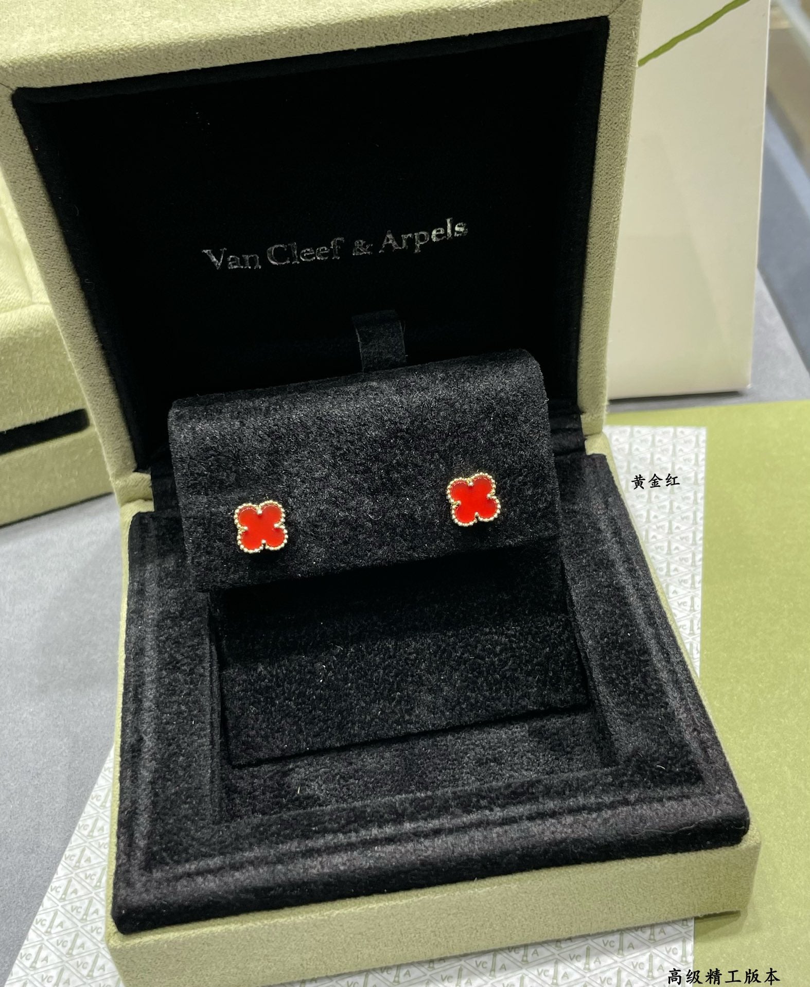 Pair of red enamel clover stud earrings in a black jewelry box