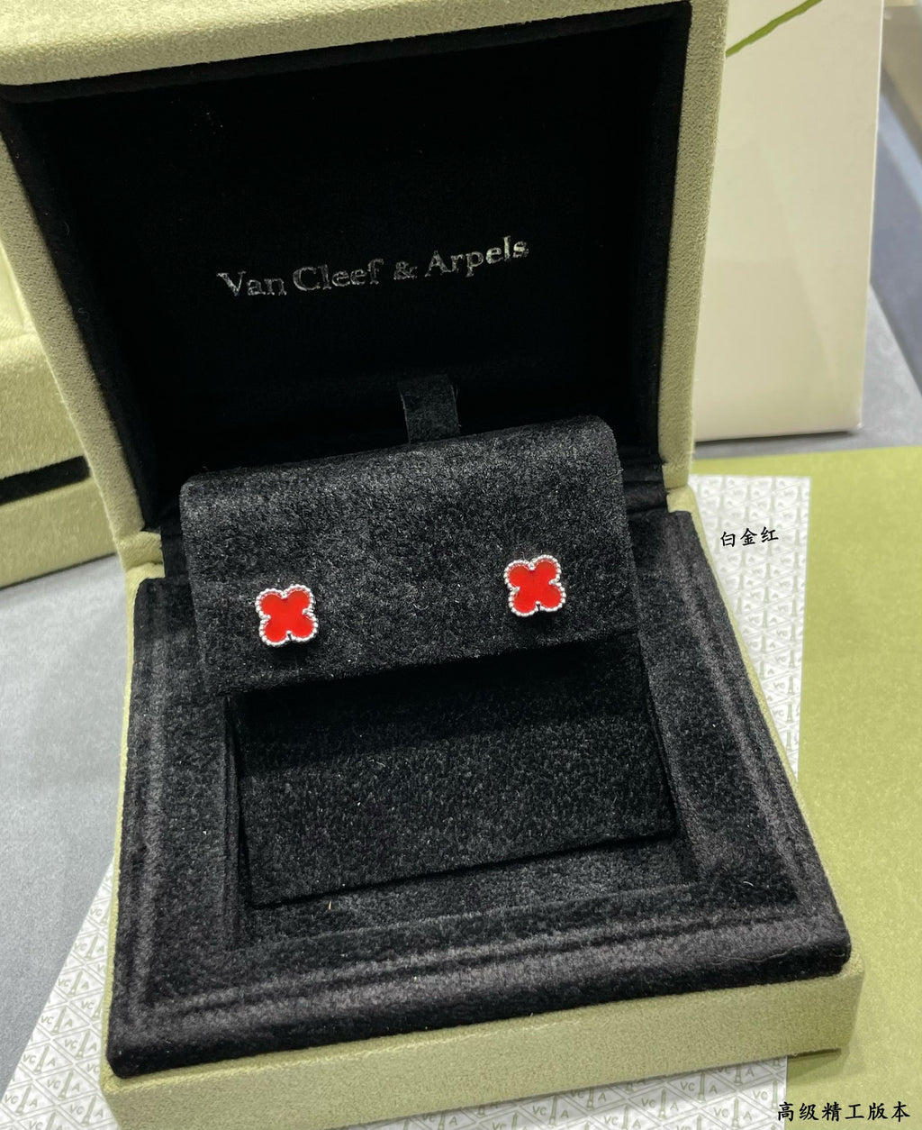 Pair of red enamel clover stud earrings in an open presentation box