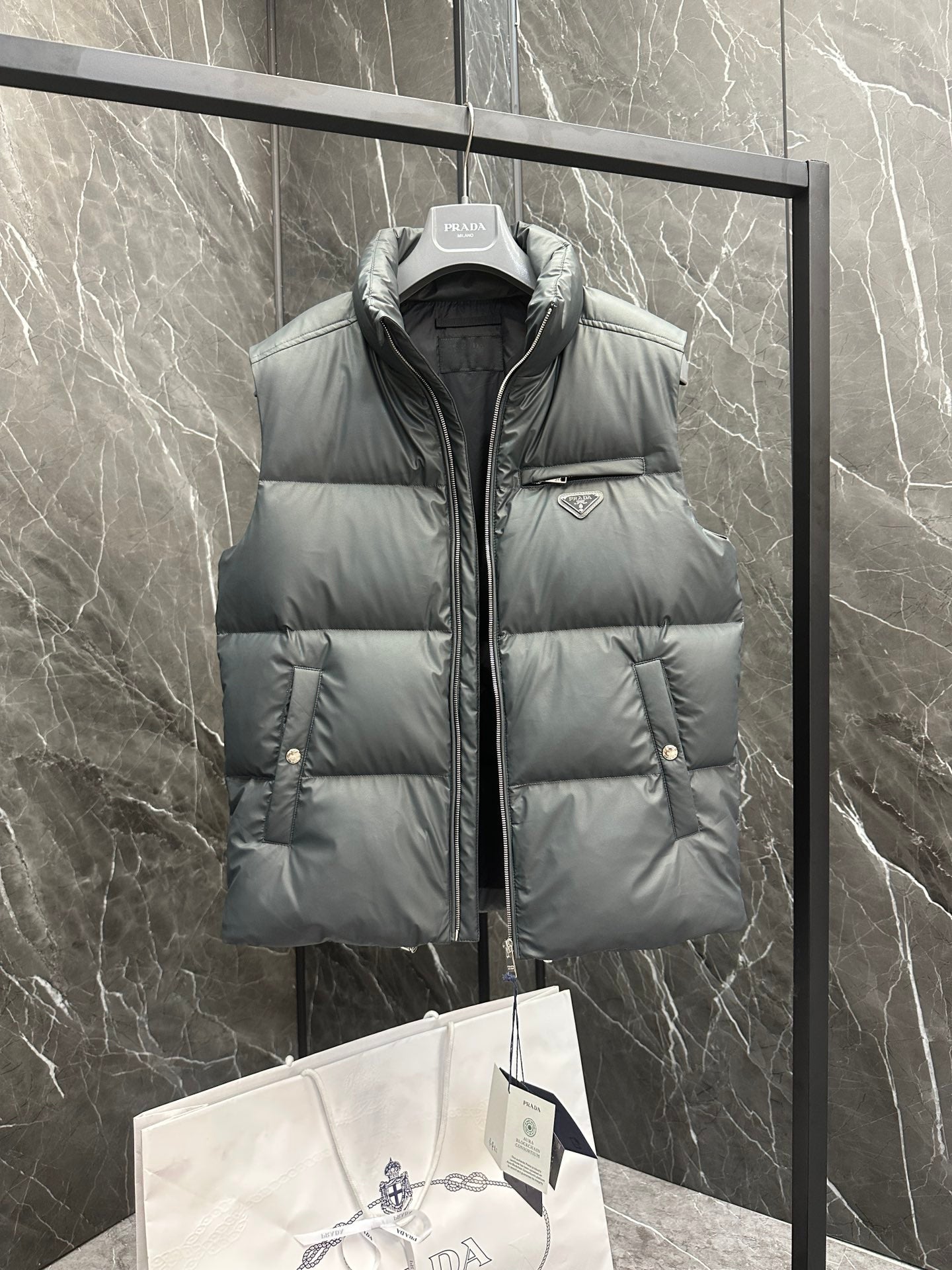 Light gray puffer vest with high collar, front pockets, and Prada triangle logo badge