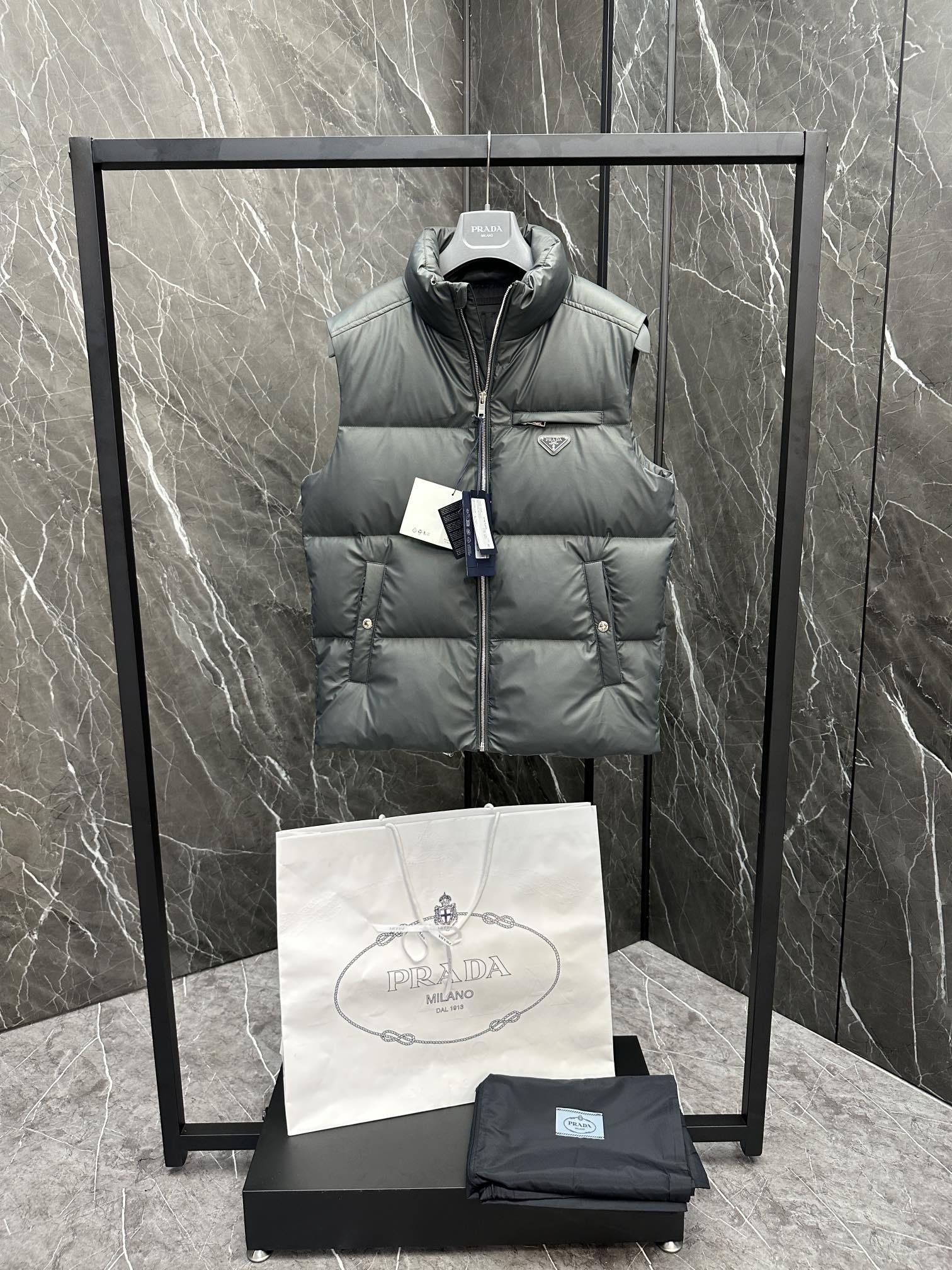 Light gray puffer vest on hanger with hooded collar, front zipper, and Prada logo