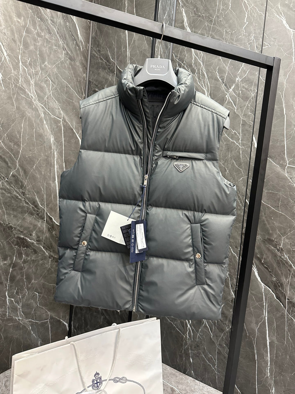 Light gray puffer vest with hooded neck, quilted panels, and Prada logo badge
