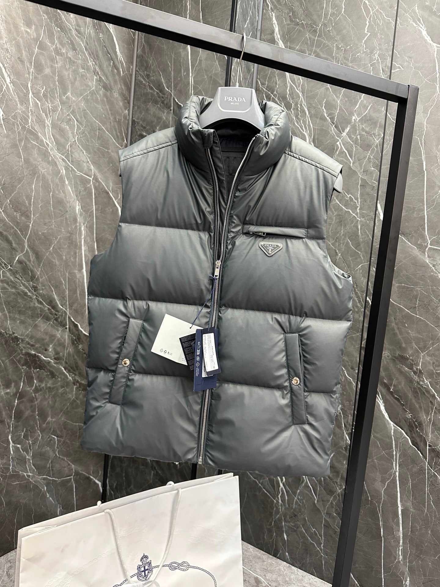 Light gray puffer vest with hooded neck, quilted panels, and Prada logo badge
