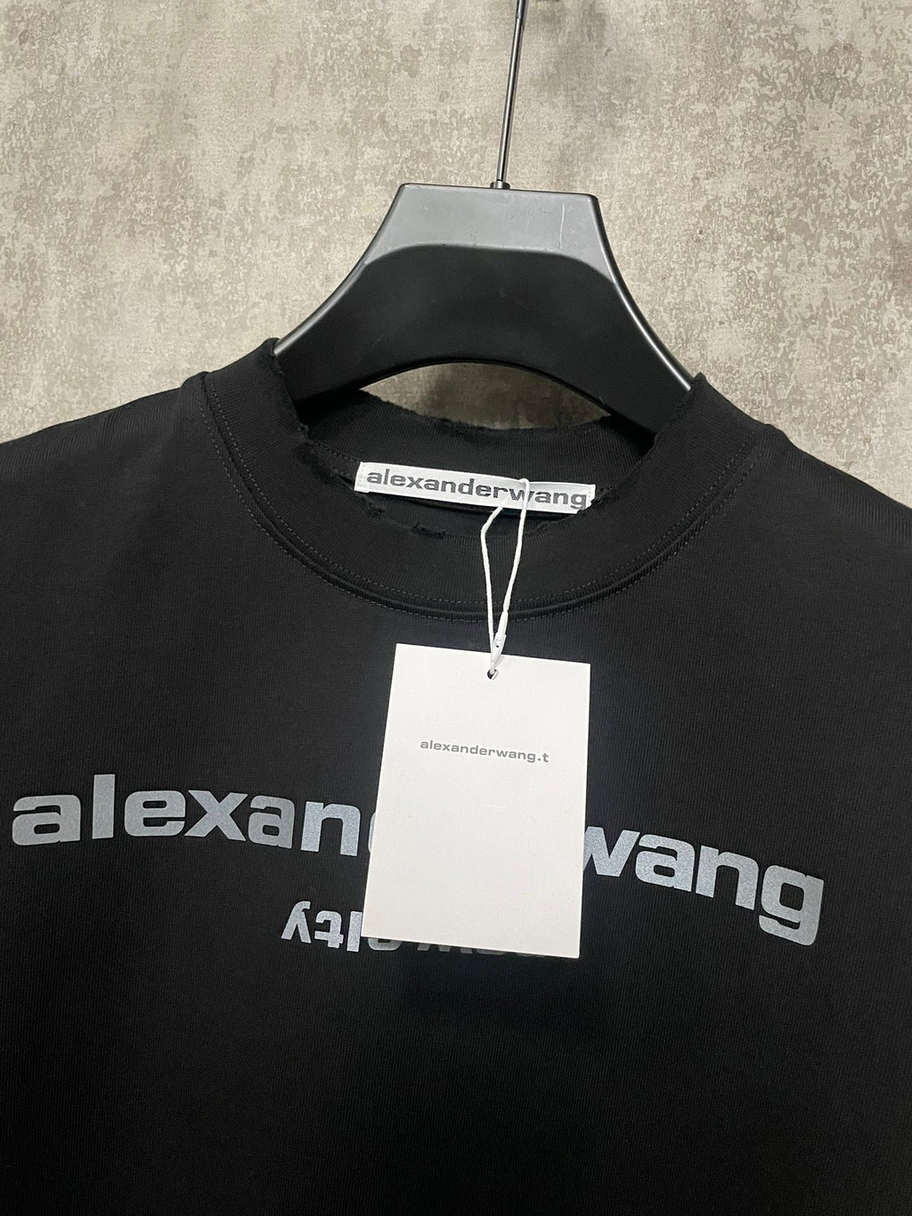 Black short-sleeve T-shirt neckline with hang tag and partial logo