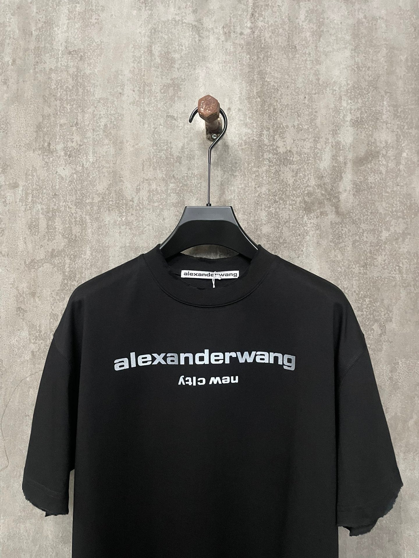 Black short-sleeve T-shirt with crew neck and front logo print close-up