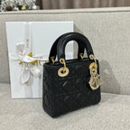 Black Dior quilted handbag with top handles, gold hardware, and dangling charm