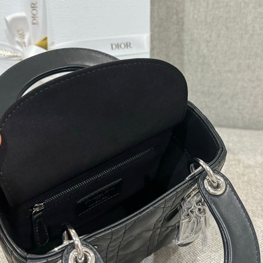 Black quilted leather Dior handbag with open top, visible zipper and silver hardware.