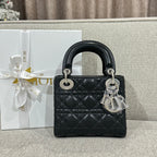 Black quilted leather Dior handbag with top handles and silver chain, front view.