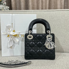 Black quilted leather Dior handbag with top handles, silver hardware and dangling charm.