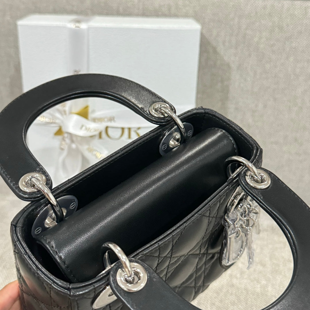 Black quilted leather Dior mini handbag open top with silver rings and chain strap.