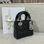 Black quilted leather Dior handbag with top handles and silver charm, angled view.