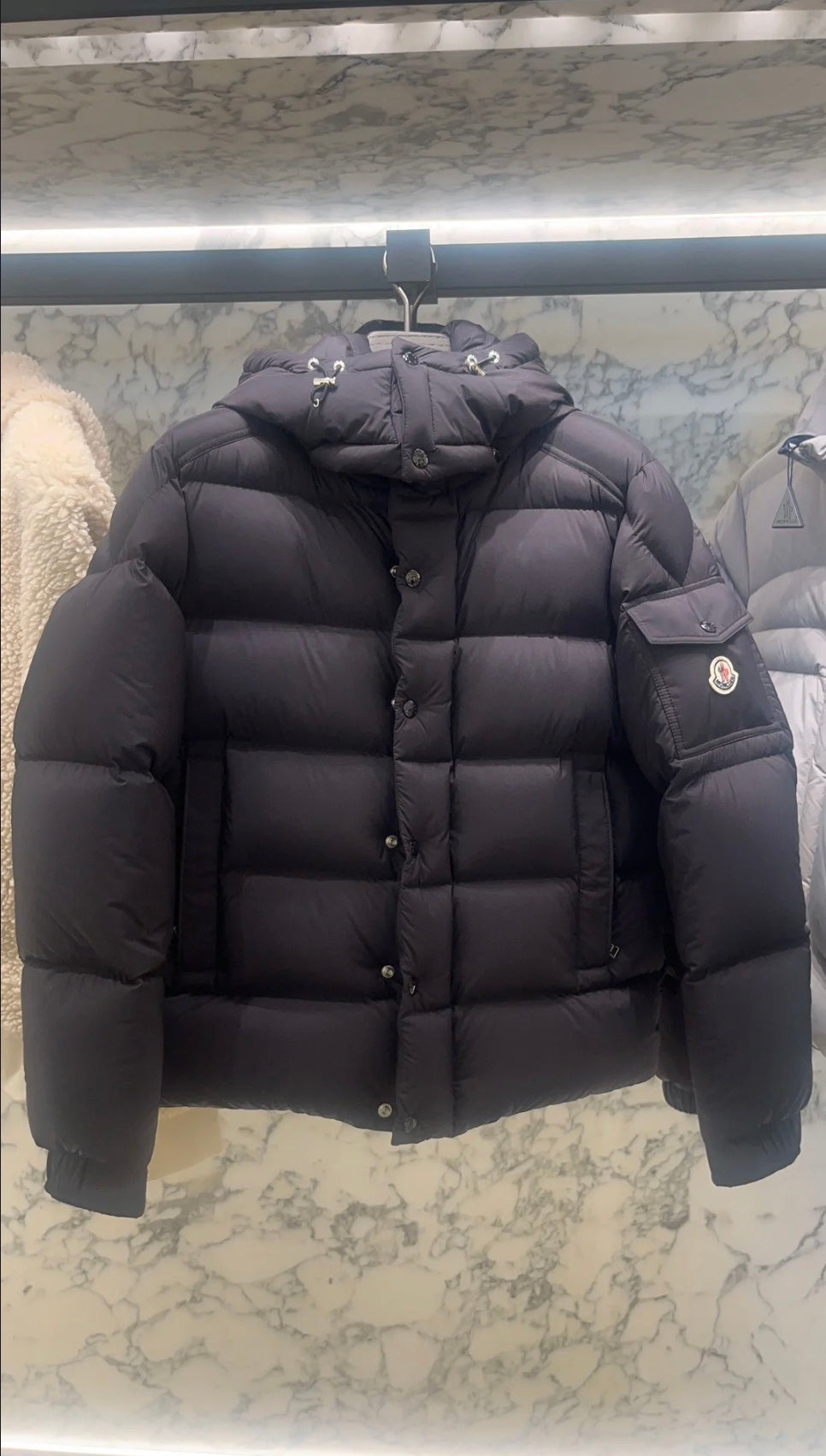 Long puffer jacket in dark color, hooded back view with quilted padding and front buttons