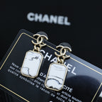 Gold-tone drop earrings with white marbled rectangular pendants on a card