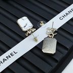 Gold-tone stud and drop earrings with white marbled pendants on a ribbon