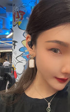 Gold-tone earrings with white marbled pendants worn by a model