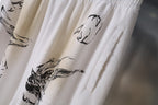 White pants close-up showing black animal-style graphic print and side seam