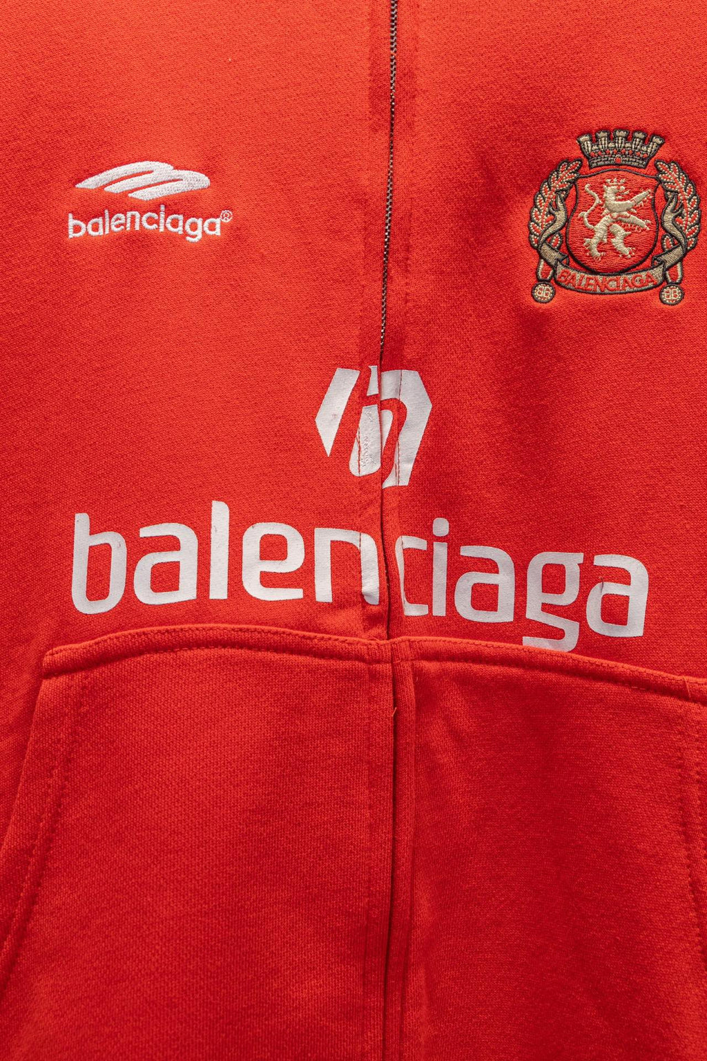 Red zip hoodie front with balenciaga logo and crest