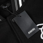 Black jacket close-up showing inner neck seam and AMIRI tag on fabric