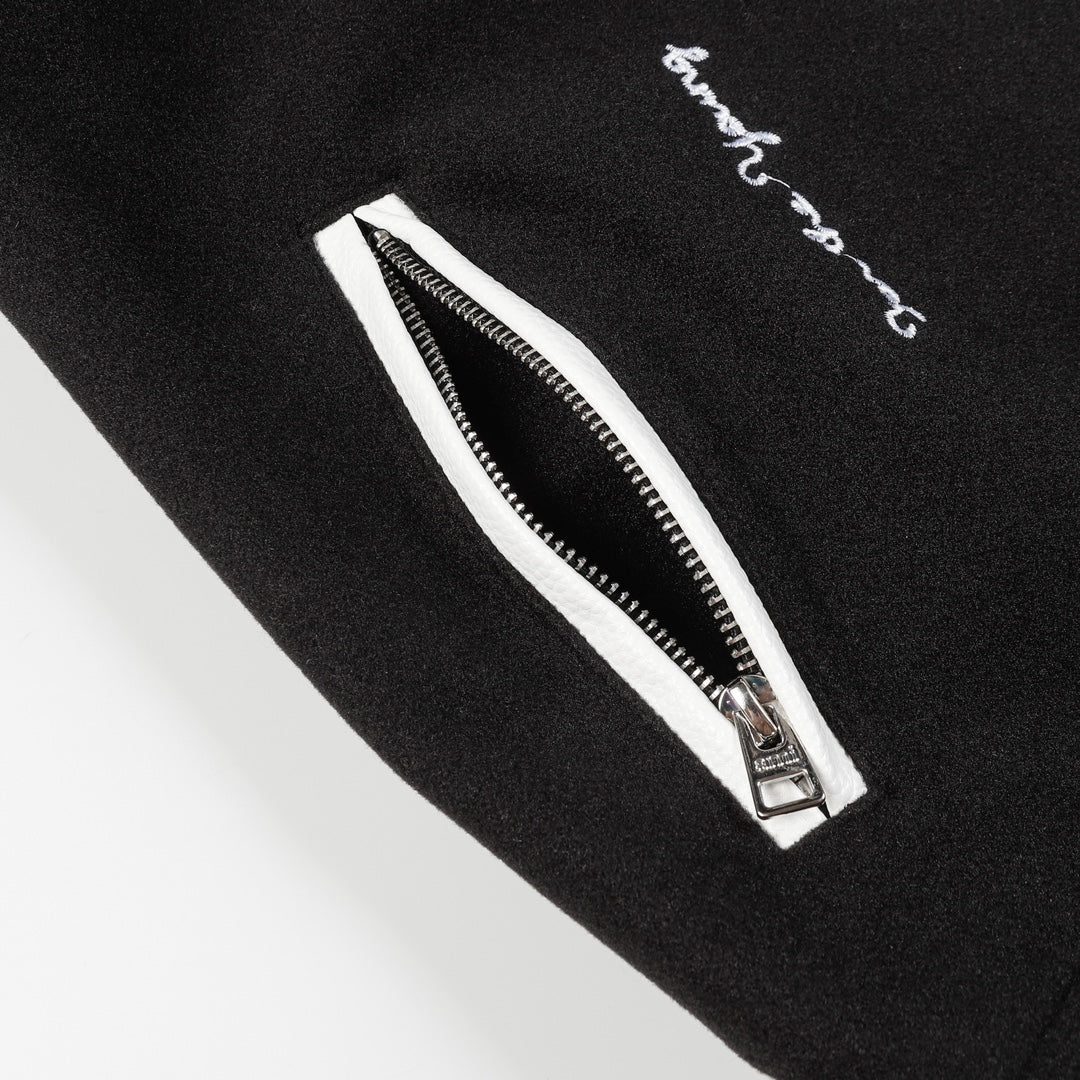 Black jacket with white zip detail and embroidered script near the zipper