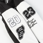 Black and white varsity jacket sleeves with embroidered patches and appliqué logos