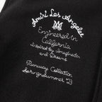 Black jacket front with white embroidered script text and small decorative lettering