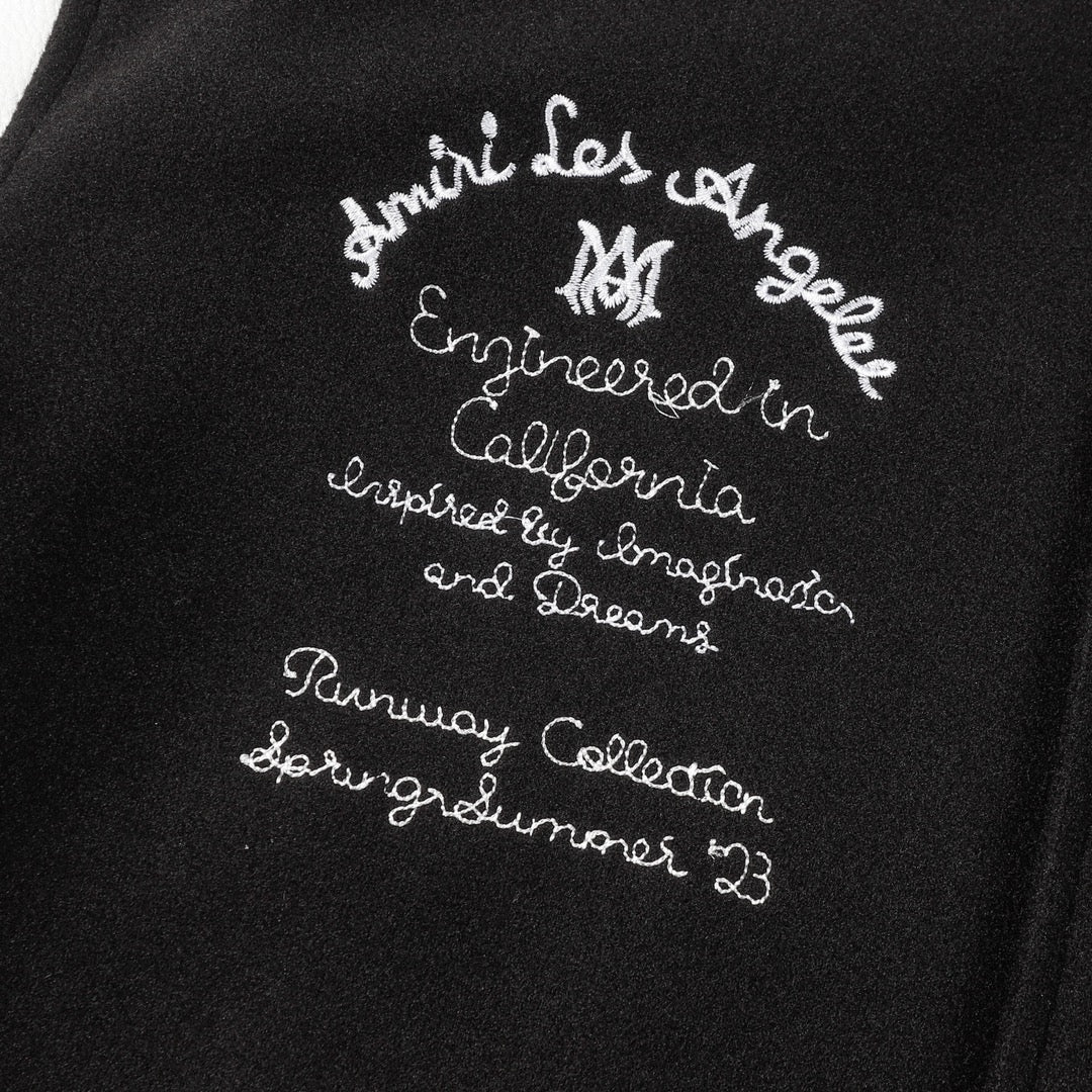 Black jacket front with white embroidered script text and small decorative lettering