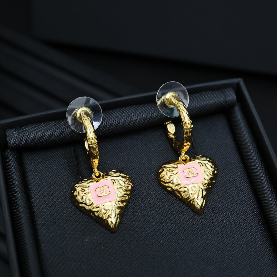 Gold-tone heart drop earrings with pink enamel logo, on hinged hoop hooks.
