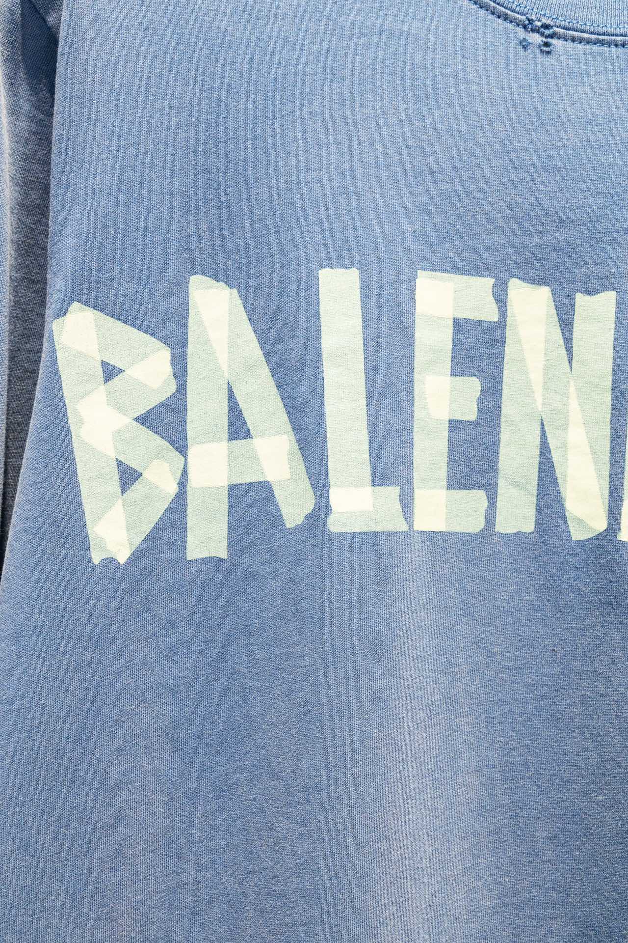 Close-up of light blue long-sleeve shirt front with oversized Balenciaga text