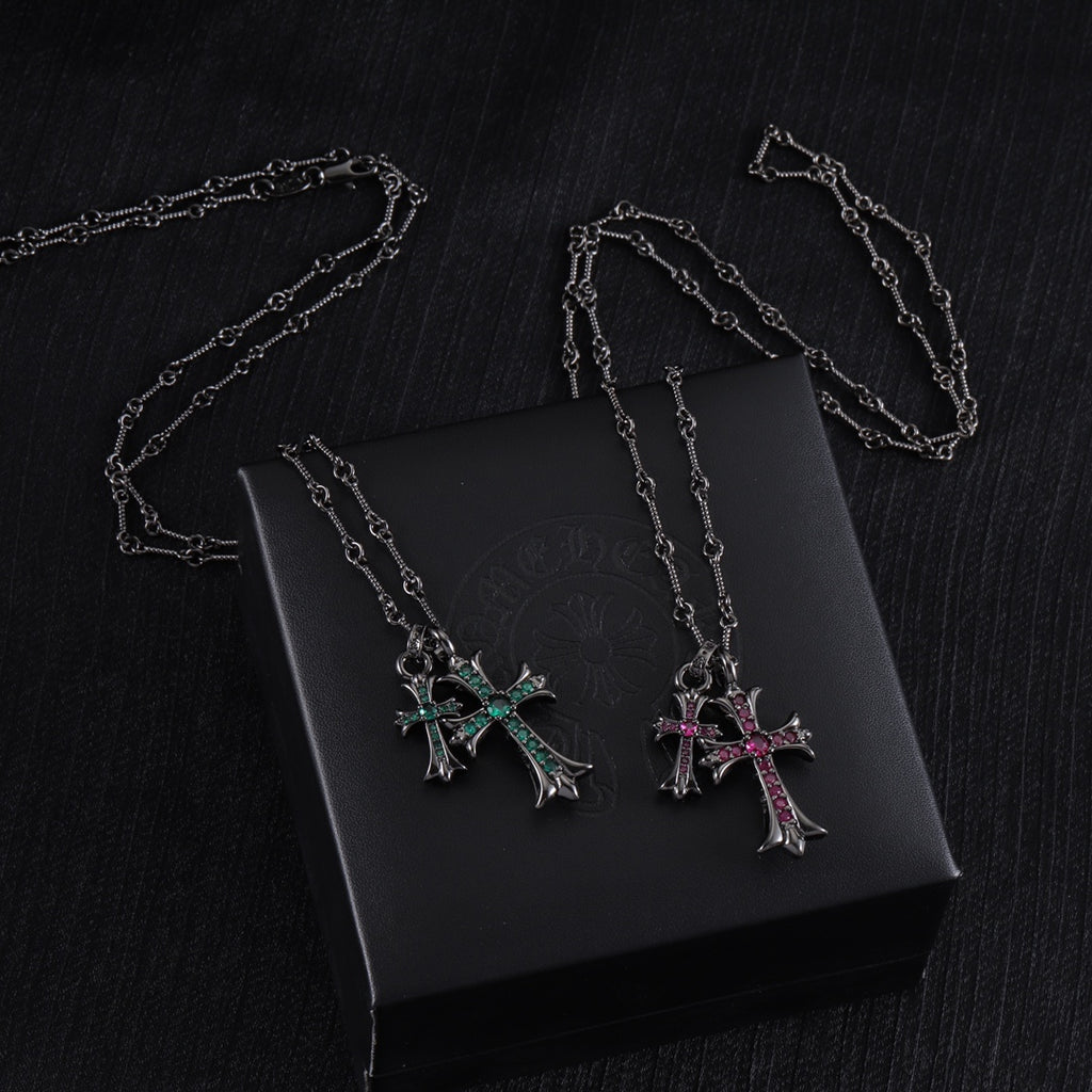 Cross pendant necklaces with silver-tone chains and colorful stone crosses on a black box