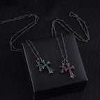 Cross pendant necklaces with silver-tone chains and colorful stone crosses on a black box