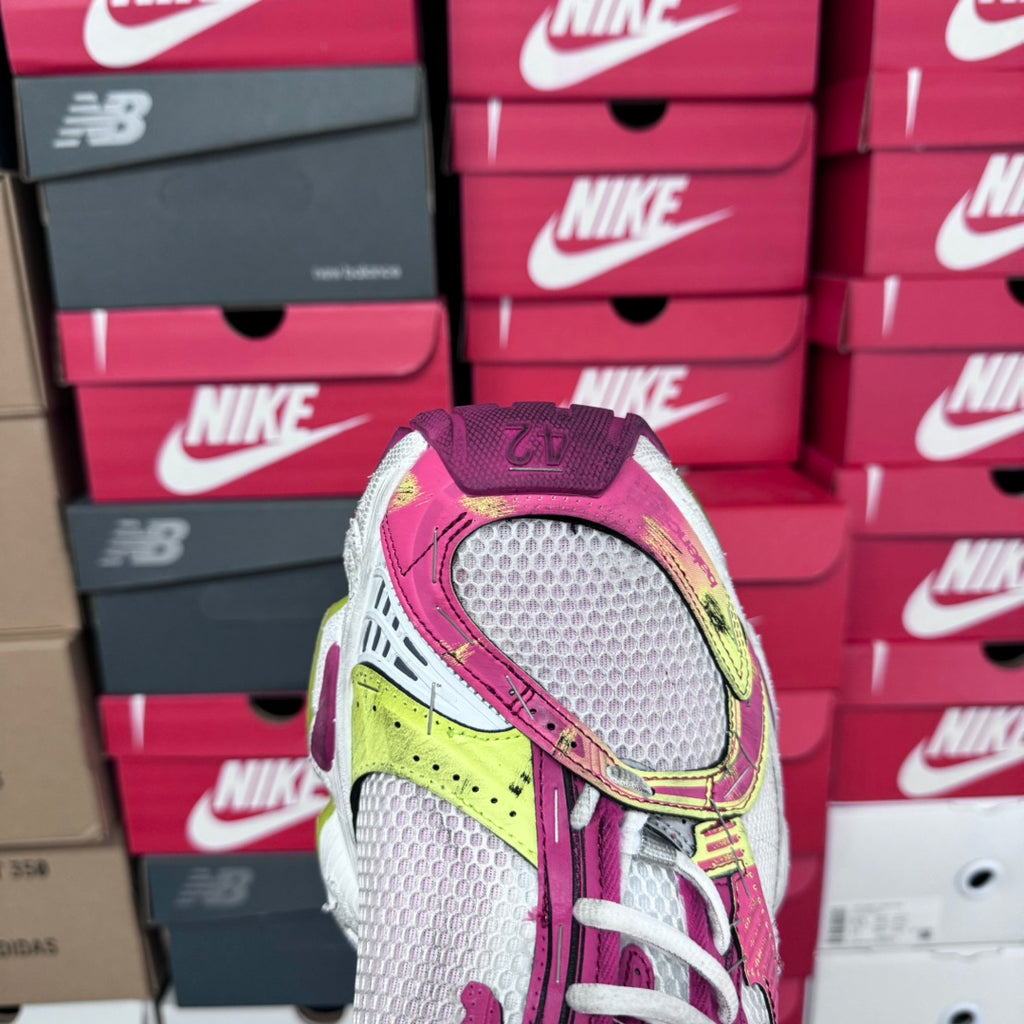 Front view of pink and gray lace-up sneakers with white laces and yellow heel detail