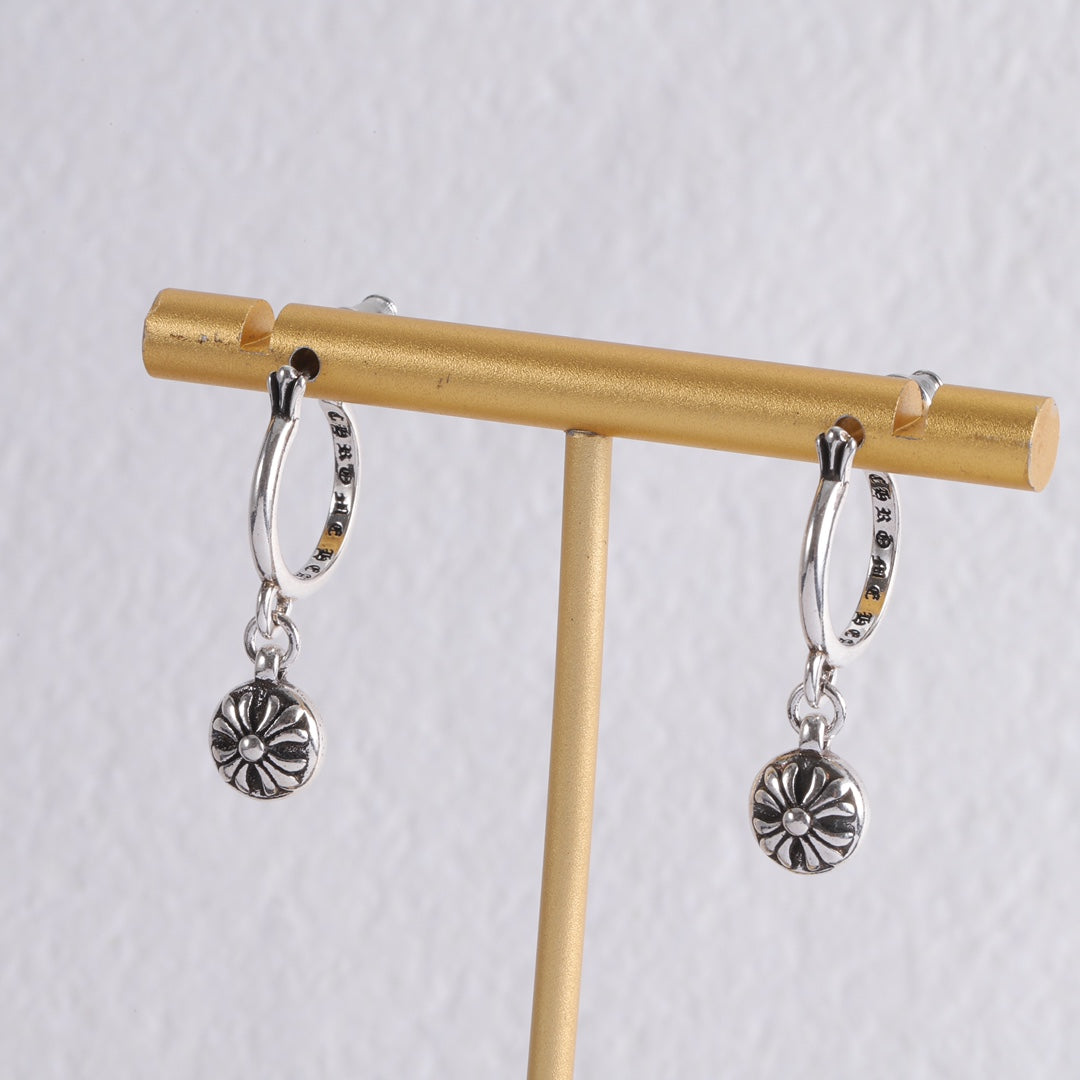 Silver hoop earrings with flower charms displayed on a small stand