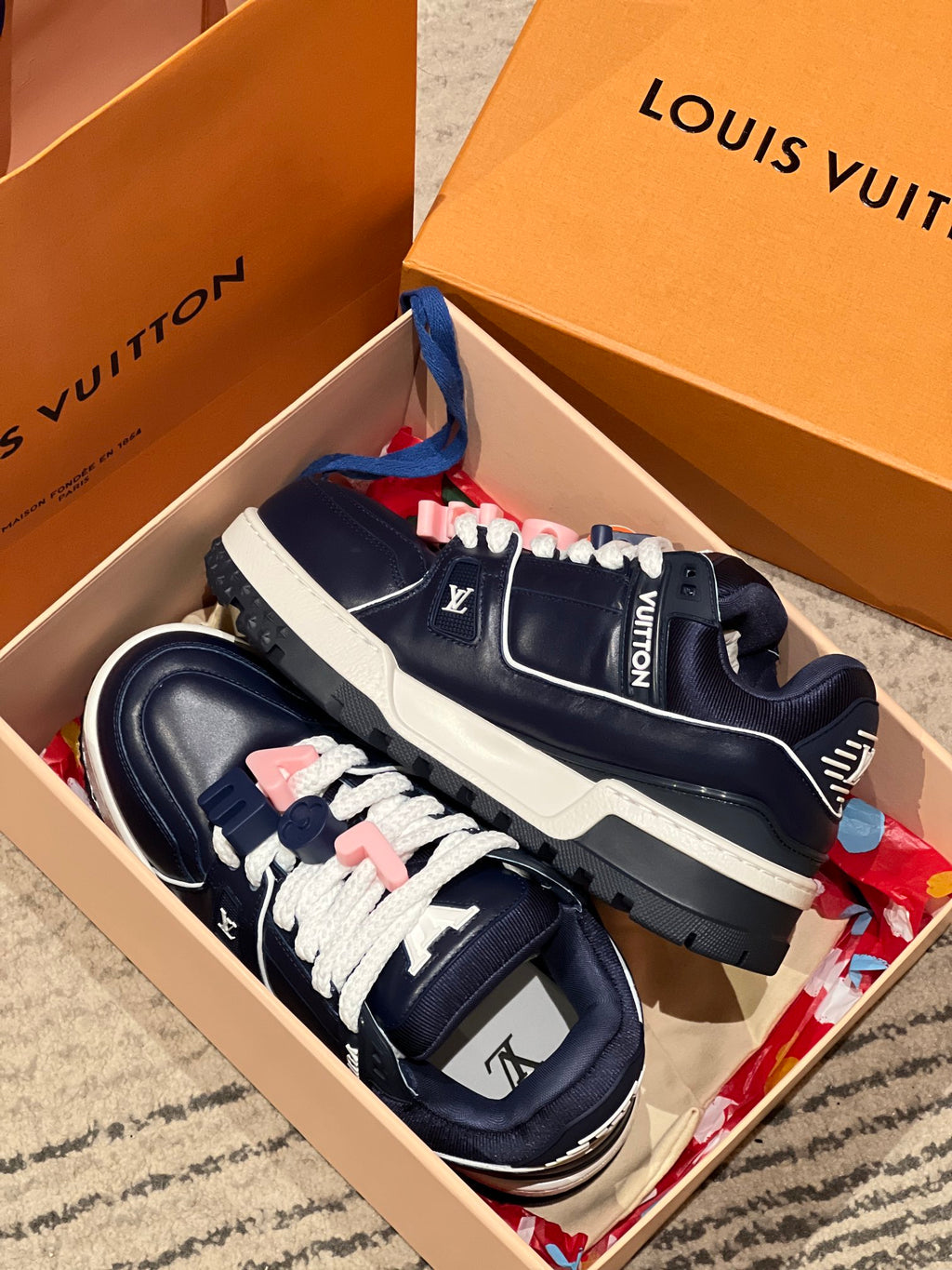 Louis Vuitton navy trainer sneakers displayed in a box with white laces