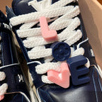 Louis Vuitton navy trainer sneakers close-up of white laces and pink charms