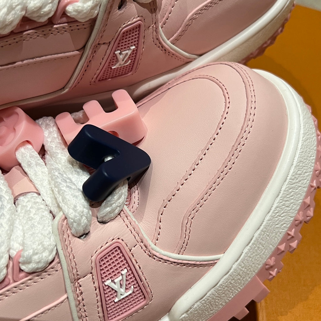 Close-up of pink sneaker upper with white sole edge and LV logo patch