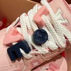 Close-up of pink sneakers: white laces with dark and light strap decorations