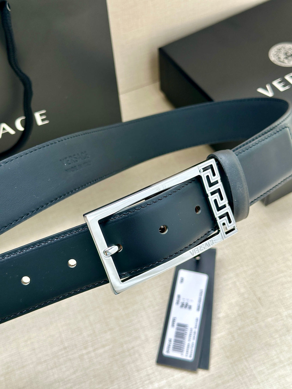 Versace leather belt close-up, dark blue strap with silver rectangular buckle