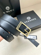 Navy leather belt with gold Greek key buckle, laid flat