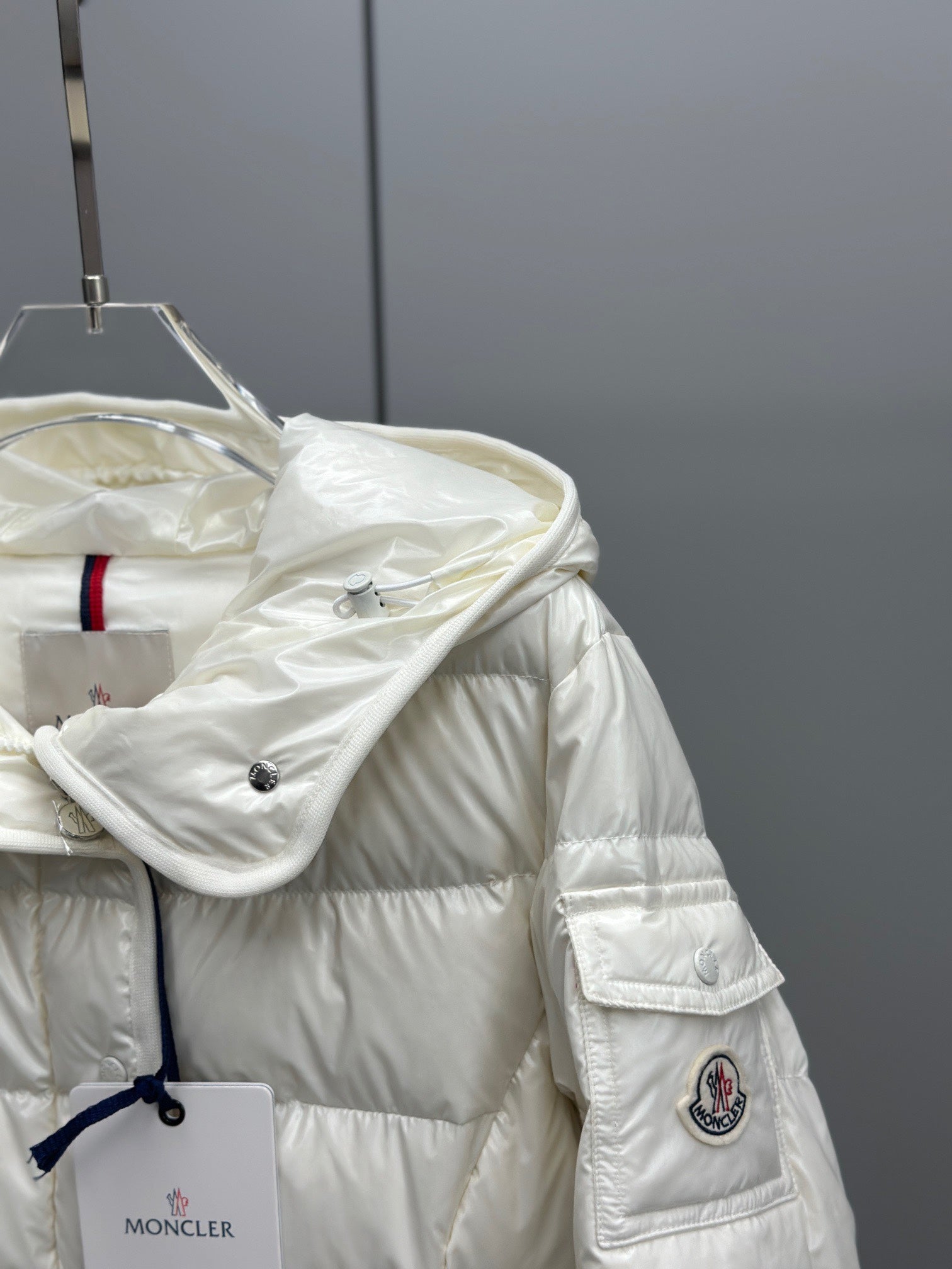 White puffer jacket with hood, raised collar, front buttons, sleeve patch detail