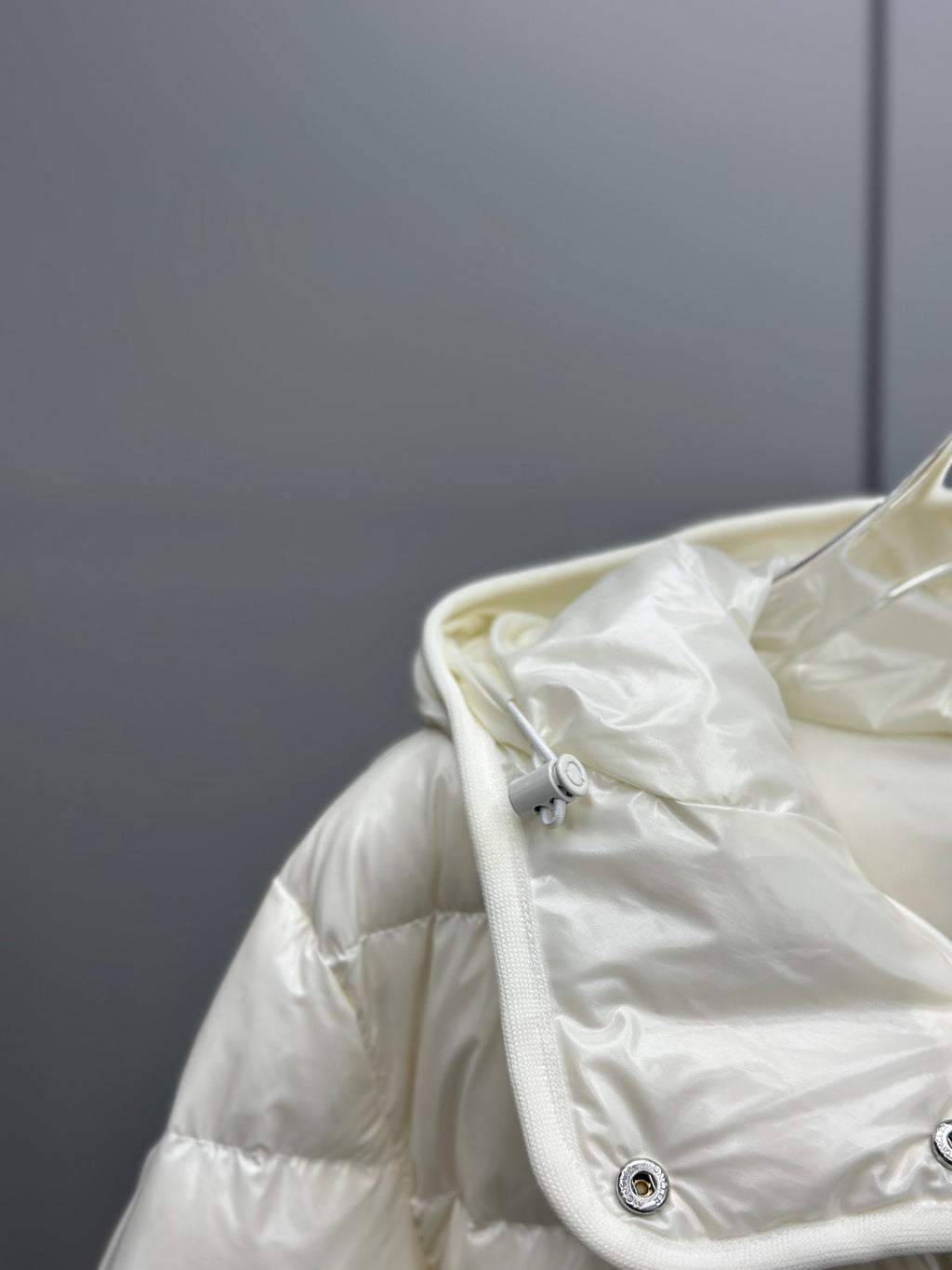 White puffer jacket hood with zipper, drawstring toggles, smooth nylon finish