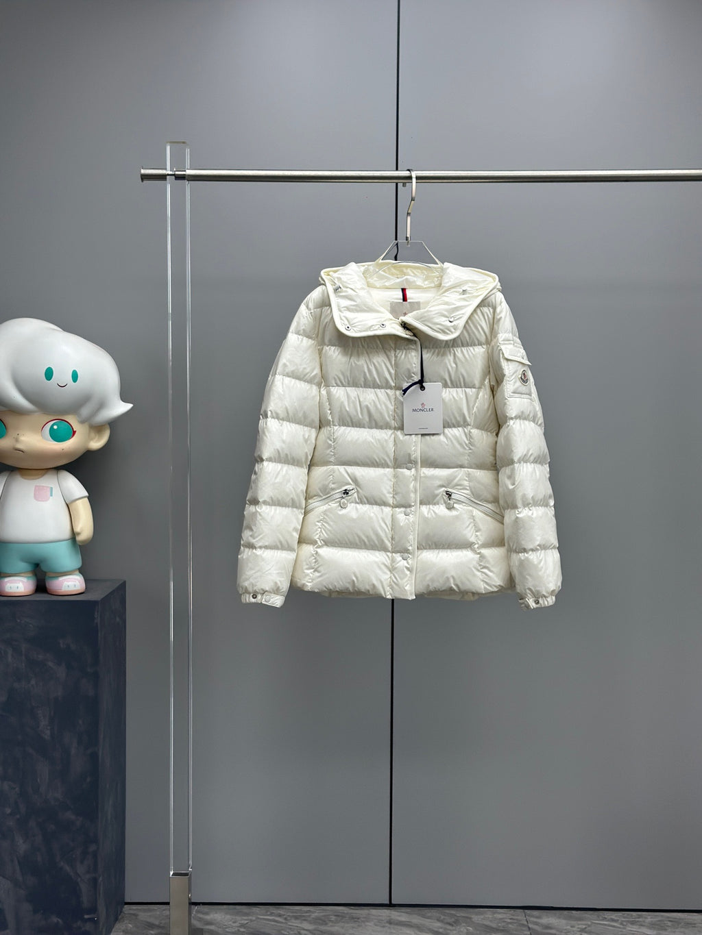 White long puffer jacket with hood and front zipper, logo tag at chest