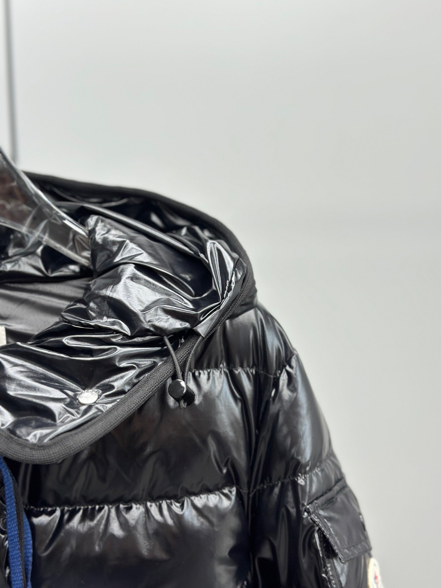 Puffer jacket chest close-up with hood drawcord and glossy quilted fabric