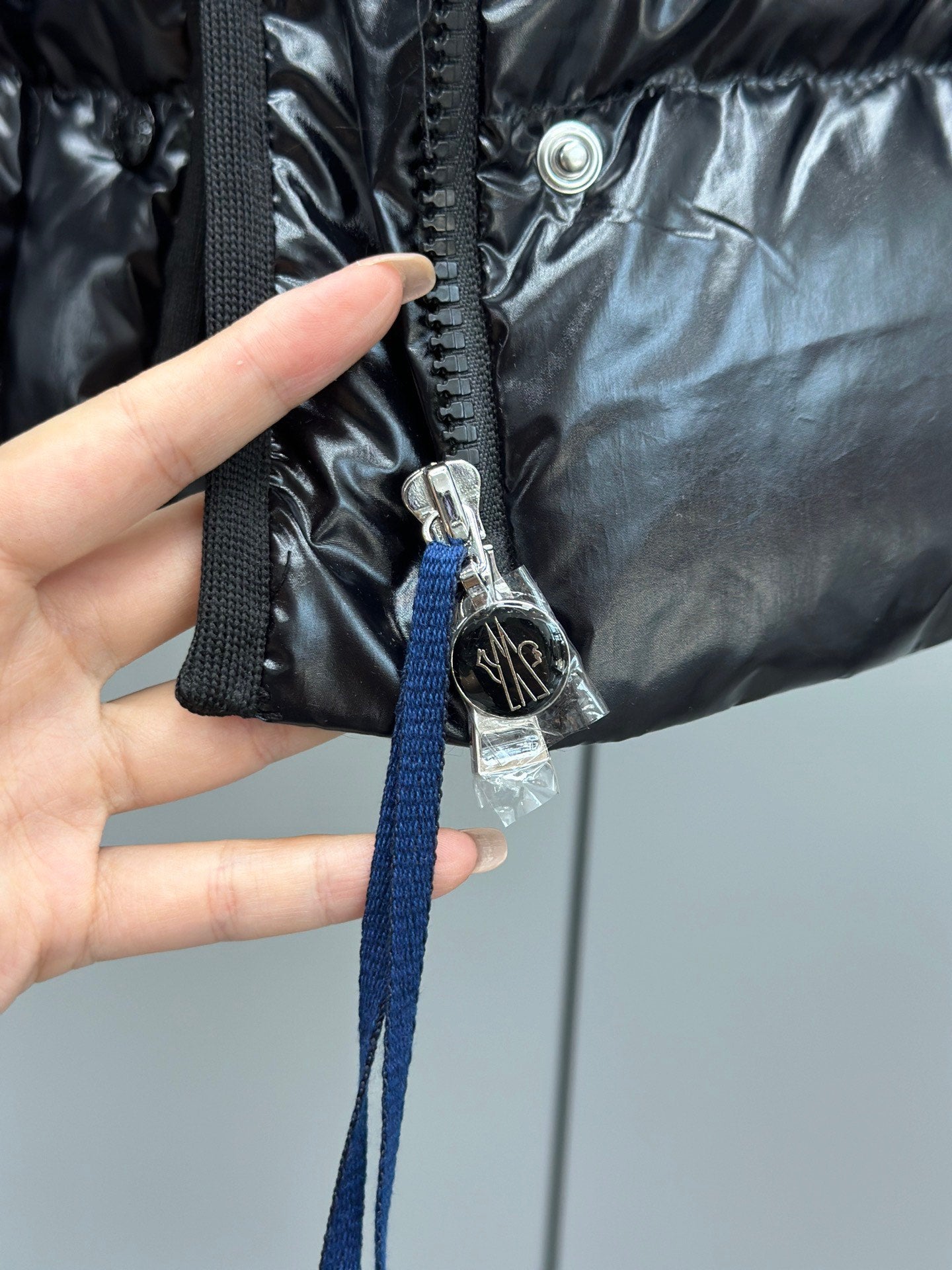 Hand holding navy drawstring on puffer jacket hood with metal ring