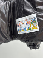 Cartoon-style patch label on pocket of glossy black puffer jacket