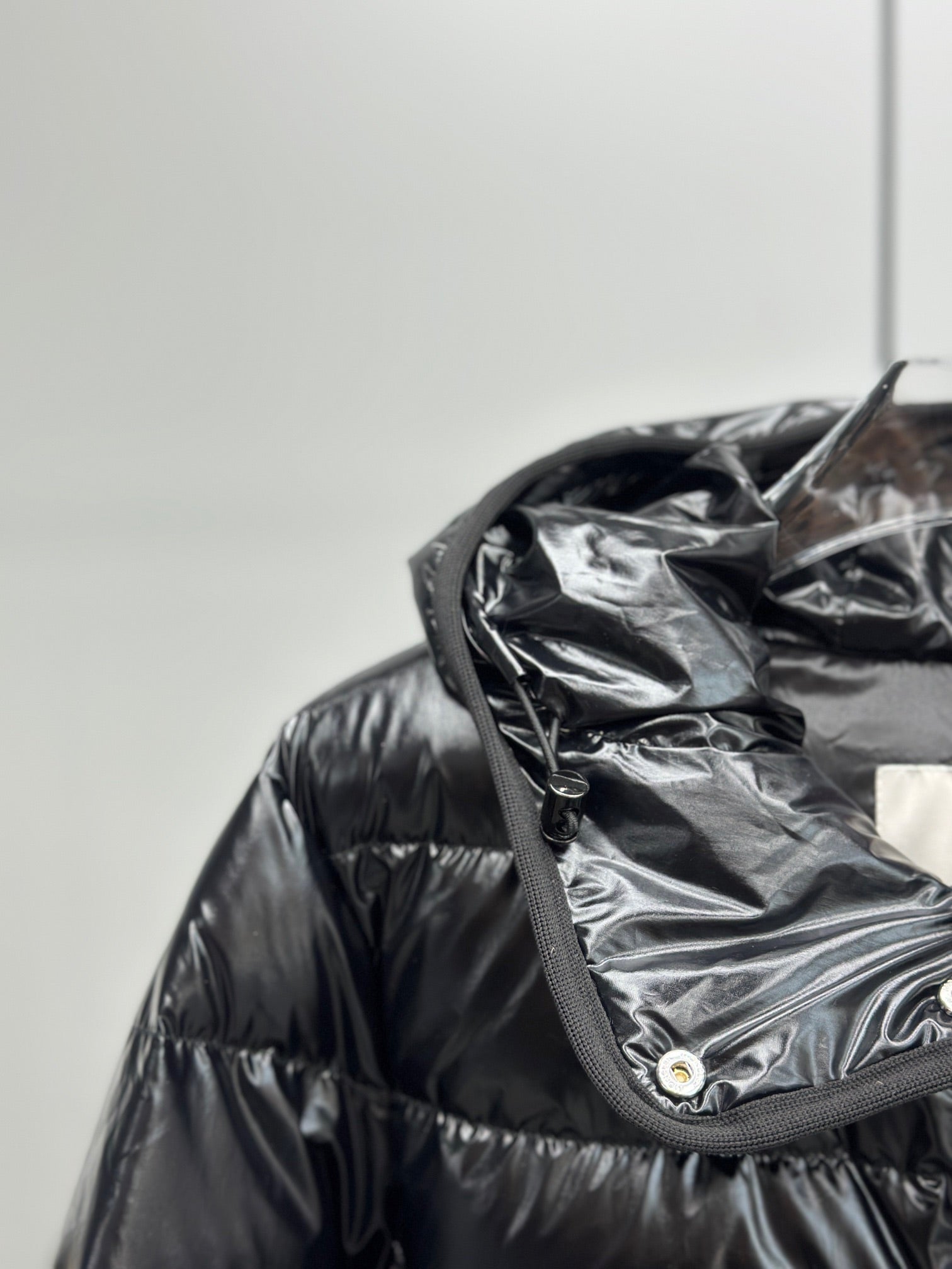 Hooded puffer jacket close-up with dark drawcord and snap button placket