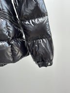 Side view of glossy puffer jacket with elastic cuff and quilted panels
