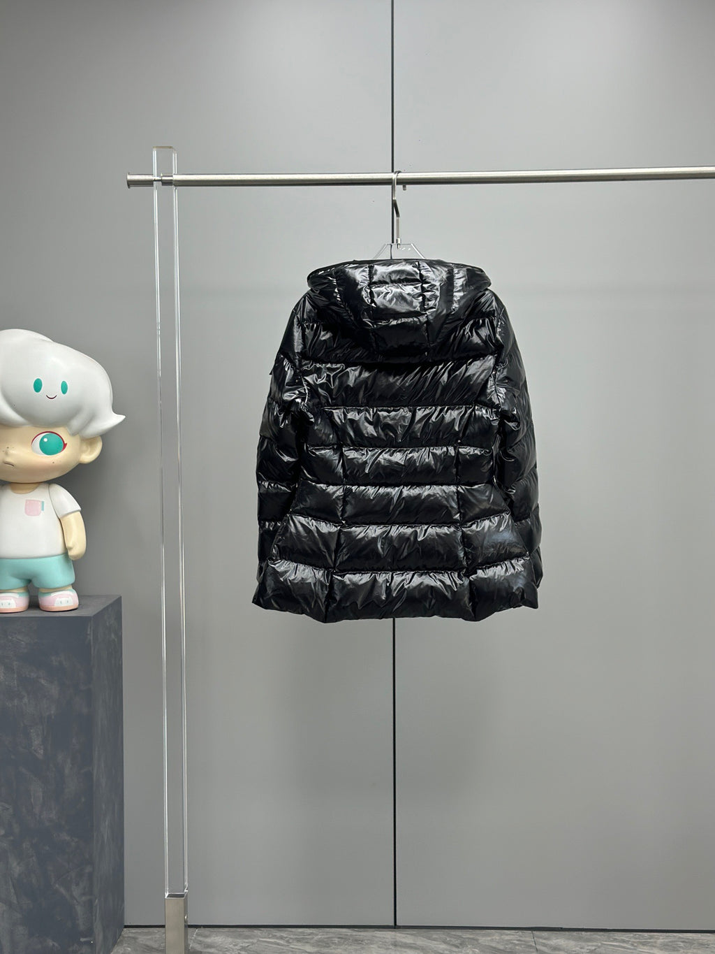 Black hooded puffer jacket on hanger with quilted horizontal baffles